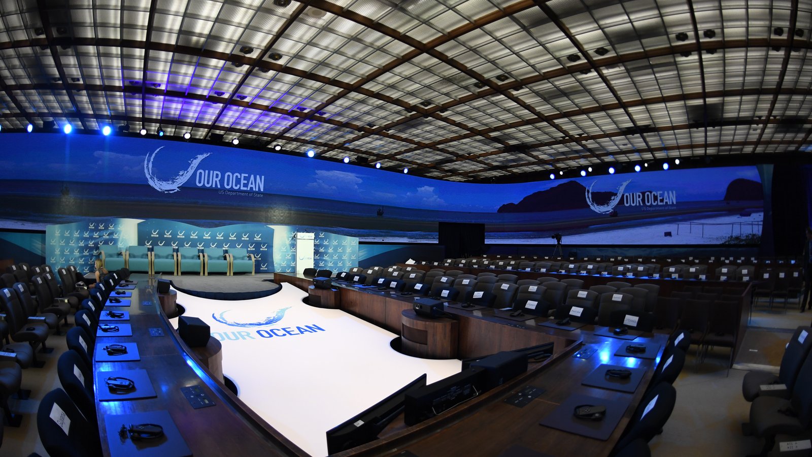 Salle de conférence aménagée avec une scène, un grand écran et des places pour les participants