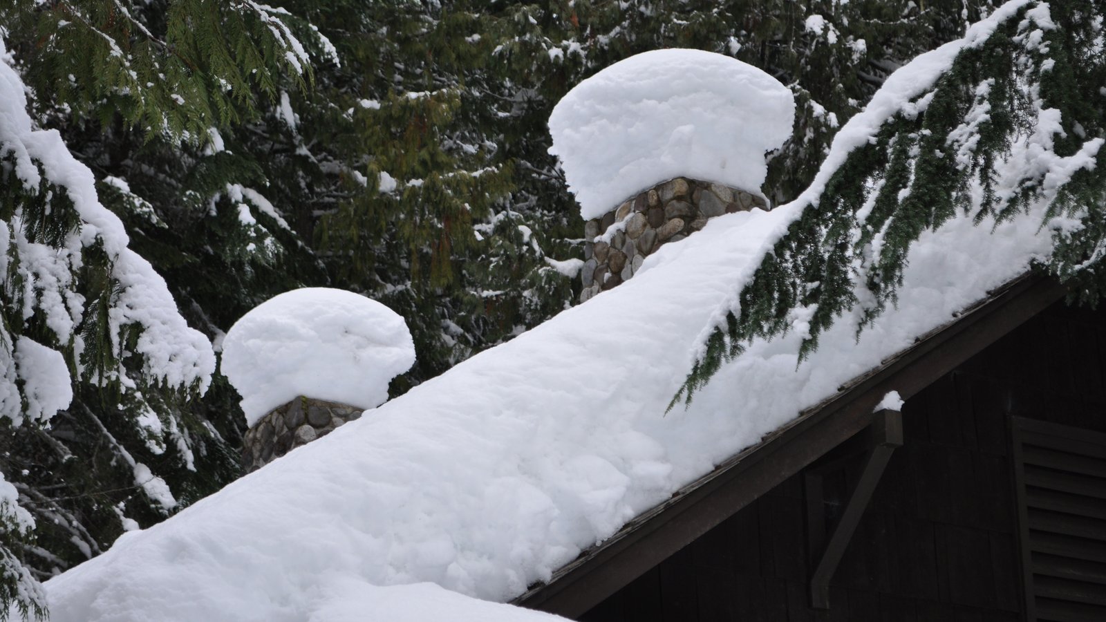 Neige accumulée sur un toit en pente et autour des cheminées